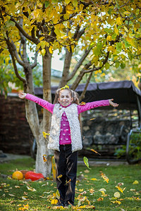 微笑绿色小姑娘把多彩的秋叶扔进空气中在花园里小姑娘扔进空气中花朵的秋叶自然图片