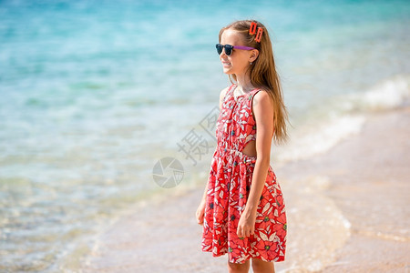 沙滩上紧贴女孩在海边背景暑假的海滩上可爱小姑娘在海滩上过暑假夏天俏皮堂图片