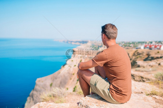 在悬崖边缘的快乐户外男人享受在山顶岩石上风景的欢快旅游者男子在悬崖海岸边缘风景积极的海洋自然图片