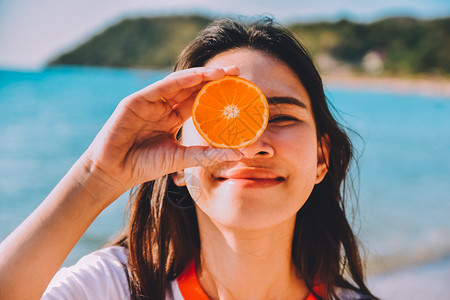 水果沙滩海滨背景中持有橙色切片的妇女夏季假日古年背景时尚海滩图片