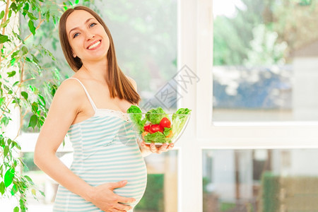 产假饮食前笑着的孕妇吃沙拉照片图片