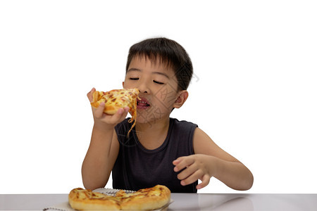 亚洲人意大利语晚餐亚洲男孩很乐于用微笑的脸吃比萨饼孤立在白背景上图片