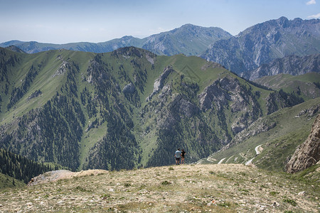 岩石成就山上藏有青蓝天空和白云的绿峡谷登山者图片