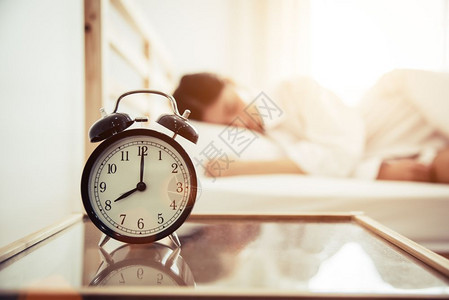 睡觉松弛清晨和懒惰时间概念睡室主题与背景美容女闹钟毯子图片