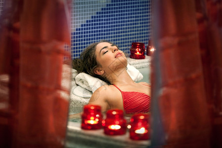 享受年轻的身体健康年轻美丽放松的女人躺在浴缸里图片