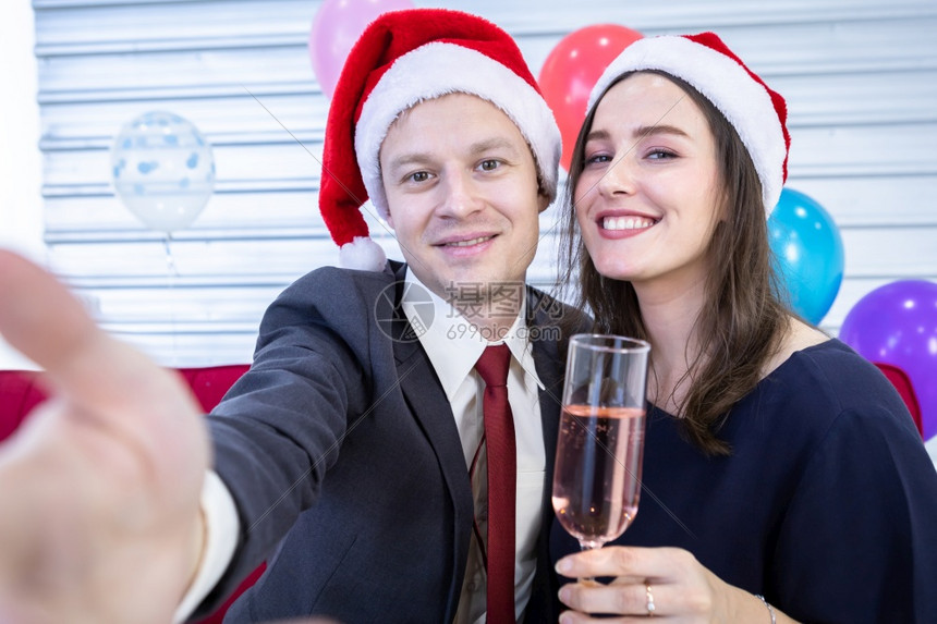 微笑假期女朋友快乐新年20的新概念快乐情侣在圣诞节和新年树夏夜晚会圣诞背景中拿着香槟杯的智慧手机自传快乐情侣图片
