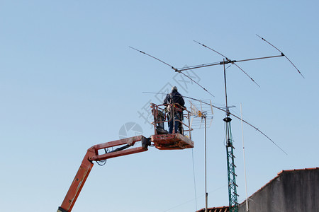 工人一种修理有蓝天线的远程电视梯操作员背景通讯维修b通信维护风险图片