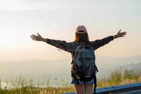 人们户外在日出海边山峰自由旅行妇女站起手来享受着美丽的自然和欢呼年轻女背包车郎快乐的图片