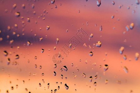 冰夜晚玻璃上的雨后水滴通过它颜色多彩的美丽日落背景中的明亮颜色水滴下笑声窗户图片