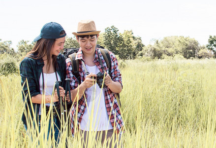 步行亚洲人绿色一对裔夫妇在夏季与背包一起旅行和徒步同时站在绿田中图片