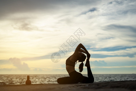 在超现实日落的海边健康概念和锻炼中在超现实日落期间从事瑜伽的妇女天空孩体式图片