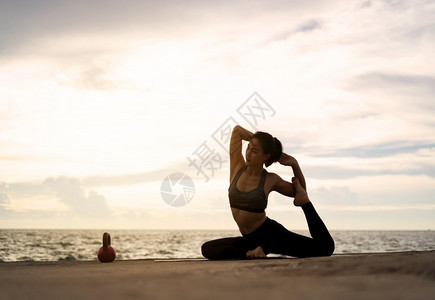 正在做合身体式超现实日落的海边健康概念和锻炼中在超现实日落期间从事瑜伽的妇女图片