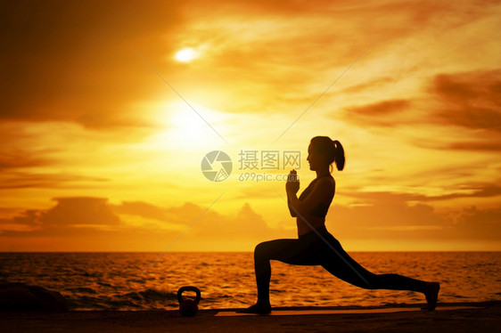 轮廓女士在超现实日落的海边健康概念和锻炼中在超现实日落期间从事瑜伽的妇女库存图片