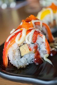 生的美食螃蟹棒寿司卷和草莓酱黑陶瓷盘上的日本菜风格鱼图片