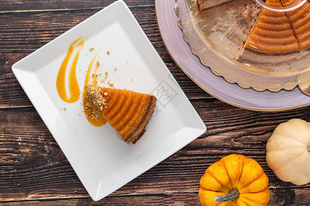 好吃的南瓜芝士蛋糕在木制餐桌上白盘馅饼感恩摄影图片