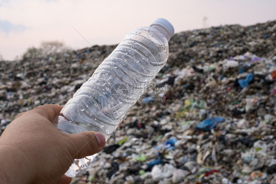 回收肮脏的人体内塑料瓶手握着大堆垃圾和污染背景泔水图片