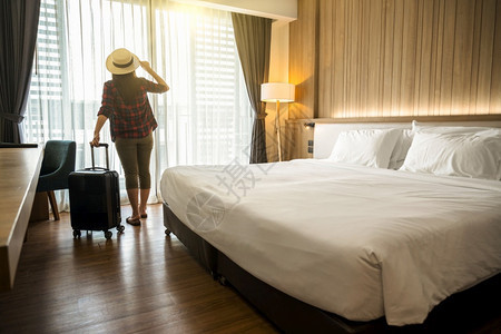 背包客幸福的亚洲旅行女客在度假豪华室内卧设计旅游和行概念时随身李站在旅馆或舍卧室招待所的里到达人们图片