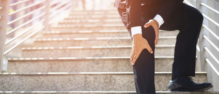 受伤身穿西装的商人有痛苦和膝盖疼问题表情在去办公室看保健概念时上下楼梯伤害麻烦图片