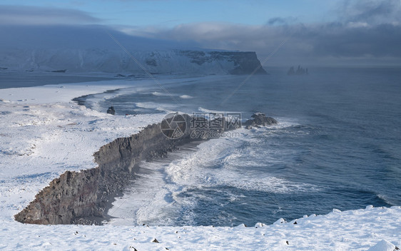 自然旅行天冰岛Dyrholaey角海岸景观的全图象在冬季与积雪覆盖海岸线的冰岛图片