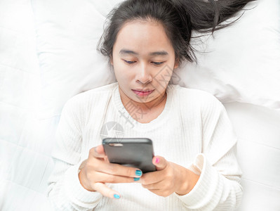 在线的亚裔女家休息时手机上读到好消息科技与放松概念Technology联系闲暇图片