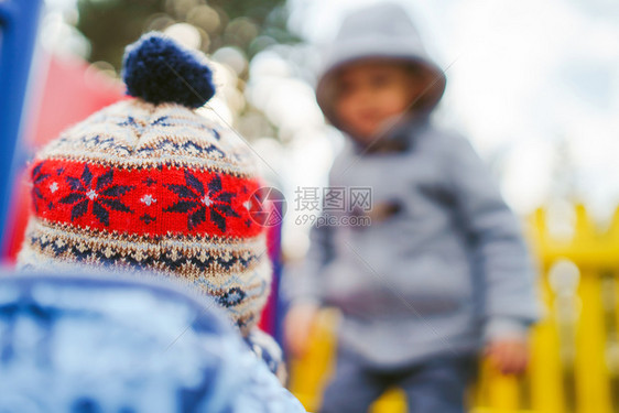 两个男孩小朋友或兄弟在冬季秋天公园玩得开心穿着冬衣和帽子玩耍的滑板或者请享用喜悦图片