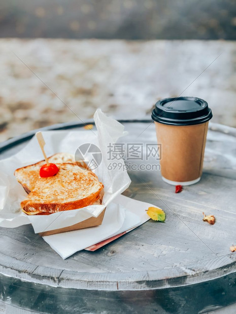 木头午餐番茄三明治纸加咖啡杯木制户外餐桌上的街头市场食品带走了这个概念注鸡尾面包和火腿奶酪配在三明治纸上咖啡杯装在木制户外桌边板图片