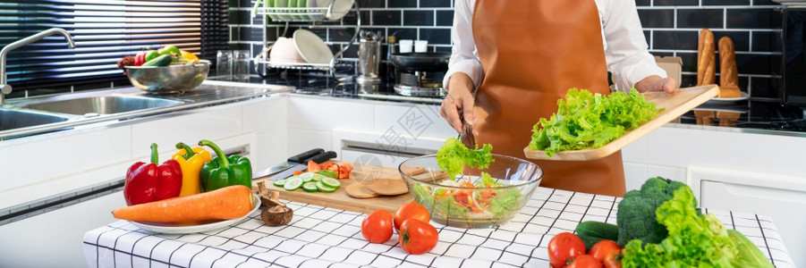 有机的黄瓜番茄正在准备健康食品的妇女蔬菜沙拉将木勺子混合在厨房里家餐室的厨房里图片