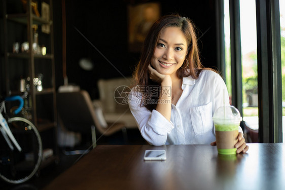 在一个成功的办公室工作过后在咖啡店里轻松地放一下时亚洲妇女微笑和快乐桌子购物杯图片