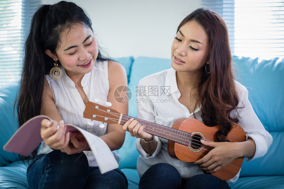 尤克里可爱的白种人两个Asiia女人玩着乐于乌鲁莱拉在家里笑着享受放松时光图片