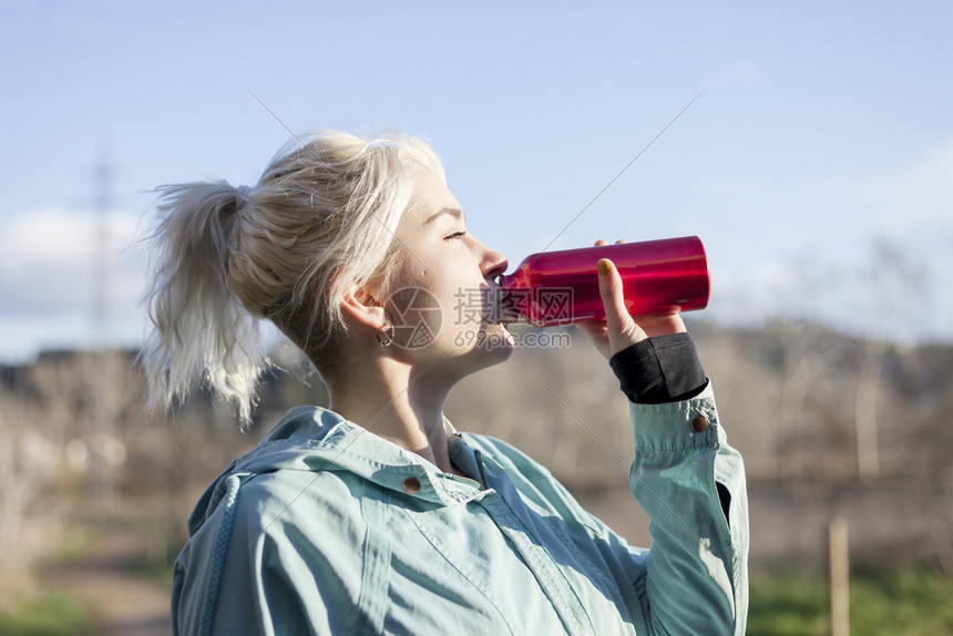 合身渴瓶子晨跑时喝水的金发女孩图片