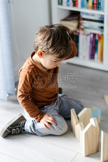 学习建造闲暇在木制或黑乙烯层化的地板上单靠开发创造力的最高视野用木玩具砖打房子形状的木玩具砖耍小天主教男孩的家庭全视仅靠木制或维图片