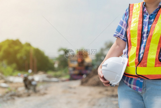 地点商业持白色安全头盔站在建筑工地前面的程妇女控制和检查建筑准确度概念组织Uniticstocontrolandcheckthe图片