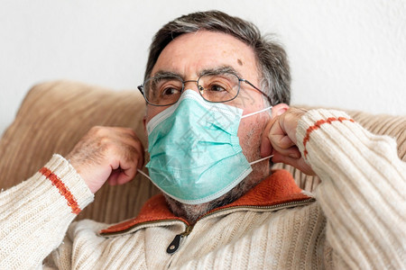 老人戴上医用口罩保护自己免受冠状流行背景图片