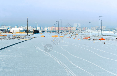 通往城市的雪覆盖道路通往城市的雪覆盖通道路过山和冬季高楼大的交叉路口过山公和高楼建筑寒冷的天空季节图片