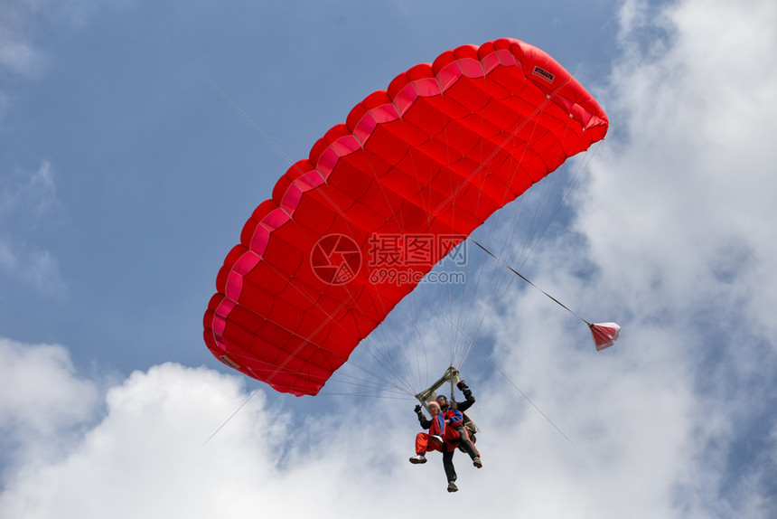 积极的串联伞兵降落在蓝天的红色降落伞串联兵降落在红色伞跳飞行图片