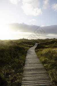 在日落前的夏夜通向遥远灯塔建筑的木板路WoodenboardwalkSummerevenbefore夕阳前的夜晚沿海旅行云图片