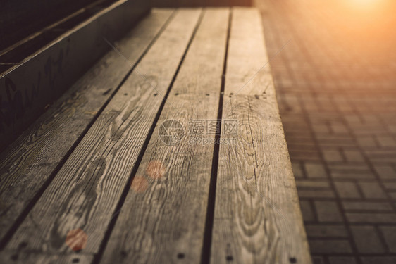 场景绿色速连科现代木制板凳深质的木制板凳在日落温暖阳光下关闭图片
