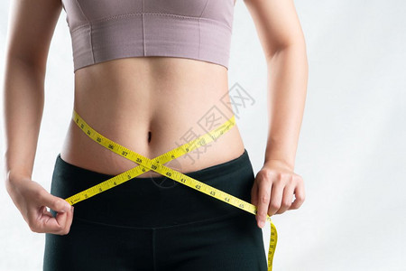 拉紧标记年轻妇女用计量胶带妇女饮食生活方式概念测量其肚子腰部的尺寸女士图片