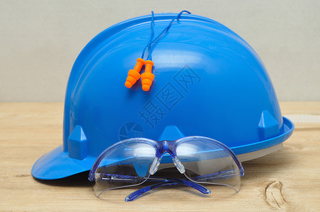 工作一顶硬帽安全眼镜和一副在木制背景上隔绝的耳塞镜片塑料图片