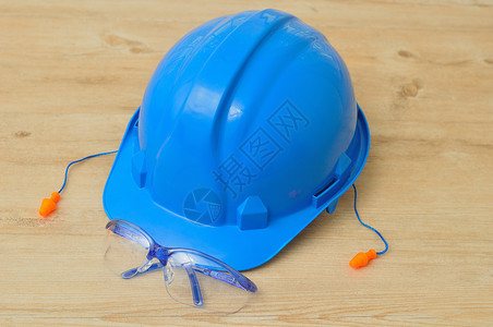 聋一顶硬帽安全眼镜和一副在木制背景上隔绝的耳塞行业劳动图片