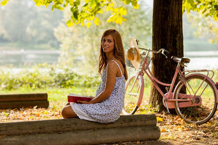 优雅坐在公园看书的棕发女人笑脸照片她写了一本书夏天闲暇图片