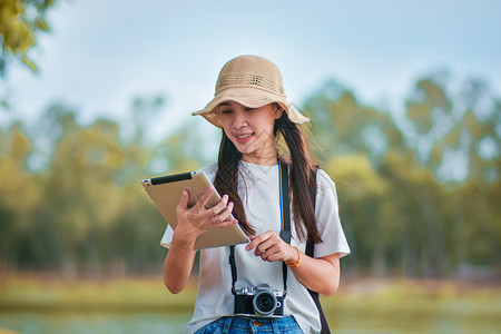 户外手拿平板电脑和相机旅游的女性图片