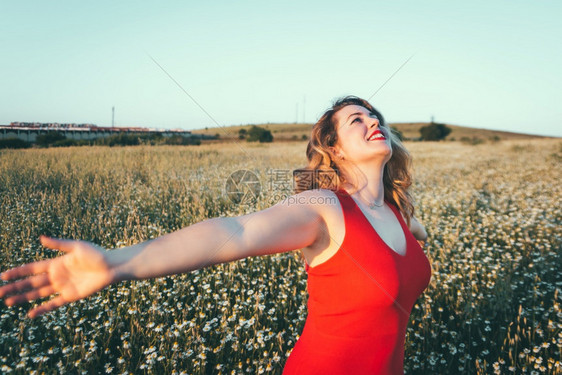 快乐的穿着红裙子女在田里享受自由雏菊女图片