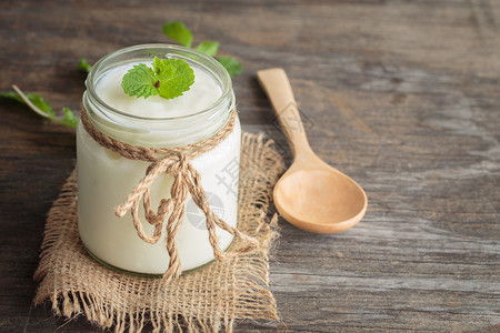 小吃产品乳制以玻璃瓶装酸奶和旧木桌板上纸薄粉为主的健康食品概念图片