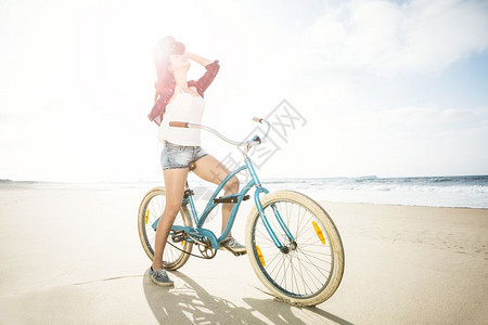 漂亮的一个有魅力年轻女子在海滩上骑着自行车锻炼假期图片