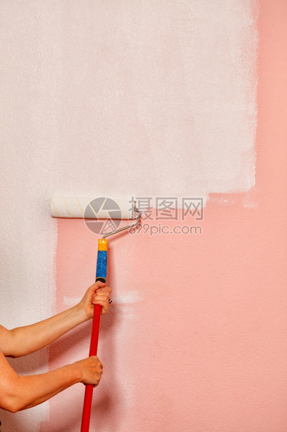 画家们在粉红色墙壁的背景下在一条长的电线杆上握着一个彩色滚动纸头画家们用粉色墙壁背面贴着一根粉色墙壁新的装饰风格粉色图片