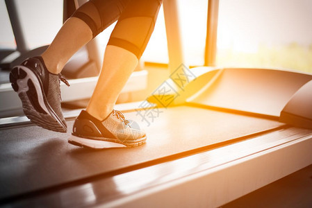 成人们女健康与锻炼活动概念健身和强力训练主题在健身房运行机或动场上跑步的健身女孩腿下部体用阳光照射温暖的语调图片