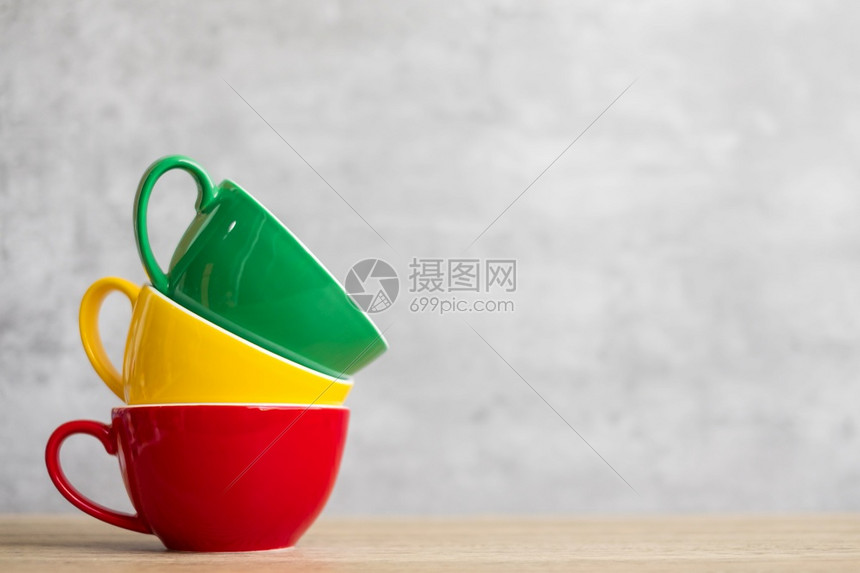 咖啡店镜像家餐桌上绿色黄和红陶瓷杯子国际咖啡日概念在绿咖啡馆的墙背景壁上挂着一串彩色咖啡杯食物图片
