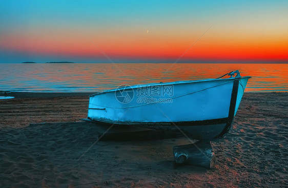 水湖沙海滩上的蓝金属船其背景是多色夜空反映于海蓝船在日落滩的蓝色岸上俄罗斯图片