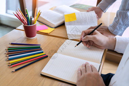 学生在书桌上帮同学辅导功课图片